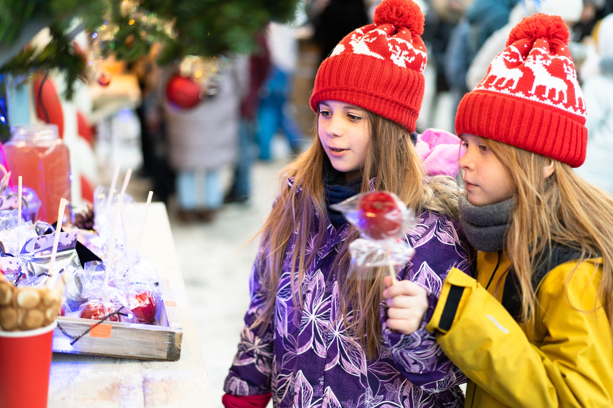 Two children in winter clothes choose homemade sweets at the Christmas market.